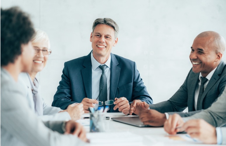 Professionals in suits talking and smiling in office meeting
